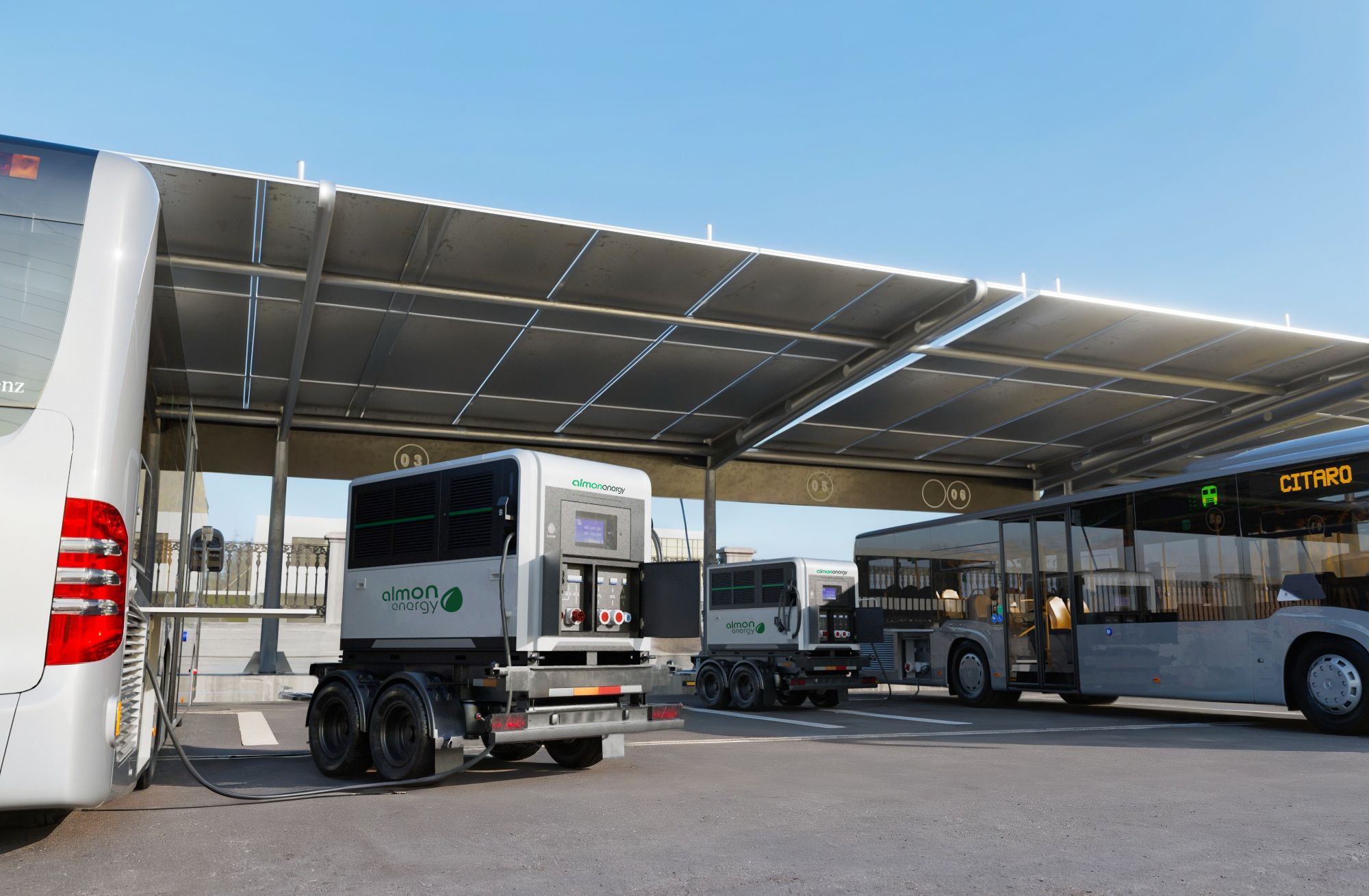 Zwei mobile Ladestationen von Almon Energy auf Anhängern laden Elektrobusse in einem Busdepot unter einem Solardach. Ein weißer Mercedes-Bus links und ein grauer Citaro-Bus rechts werden durch die mobilen Einheiten mit Strom versorgt.