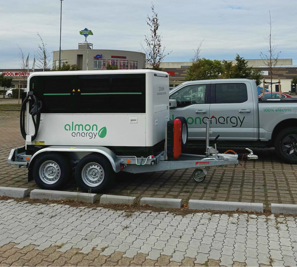 Mobiler Batteriespeicher auf PKW-Anhänger neben Servicefahrzeug für flexible Flotteneinsätze