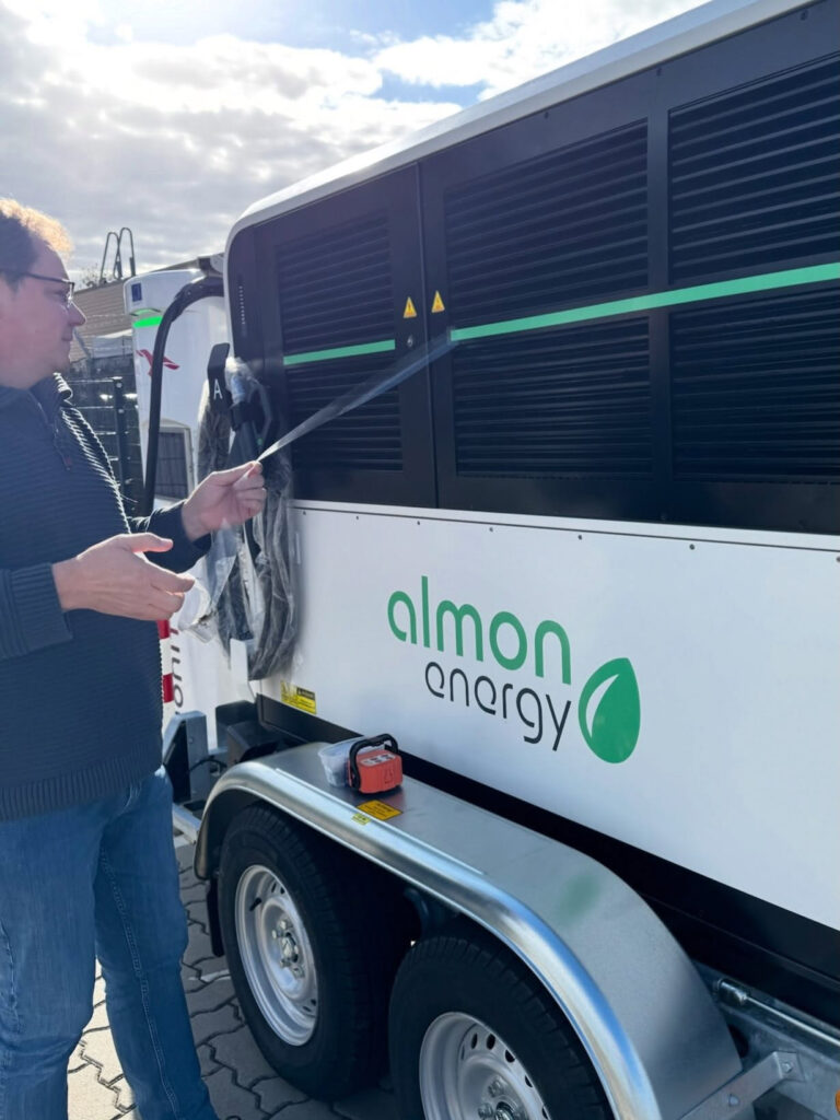 Oliver Nee präsentiert den mobilen Batteriespeicher und Schnelllader MX-210 von Almon Energy auf einem Anhänger